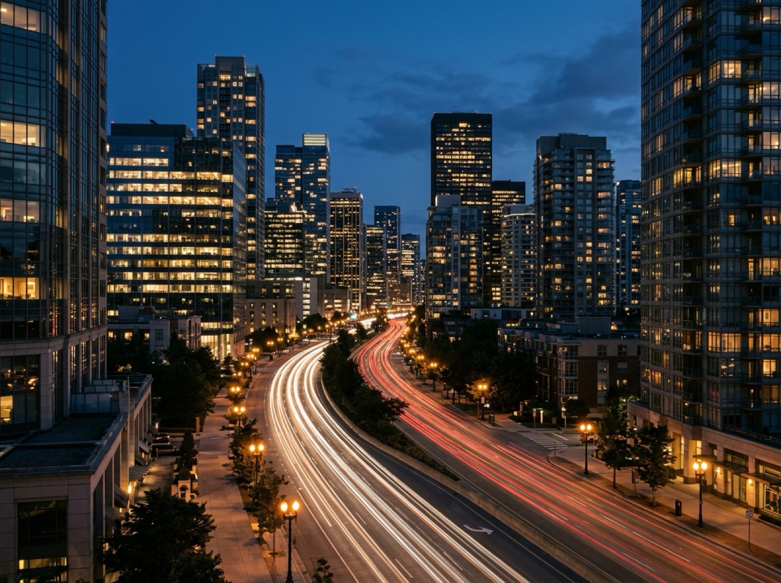 Evening city boulevard with flowing traffic light trails between lit towers